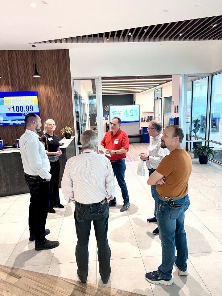 Group of people in a bank lobby, some standing in a circle, others near a counter.