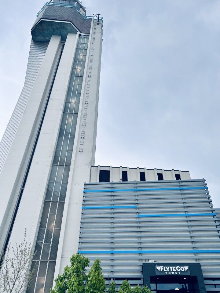 Tall white airport control tower with a blue and gray building attached.
