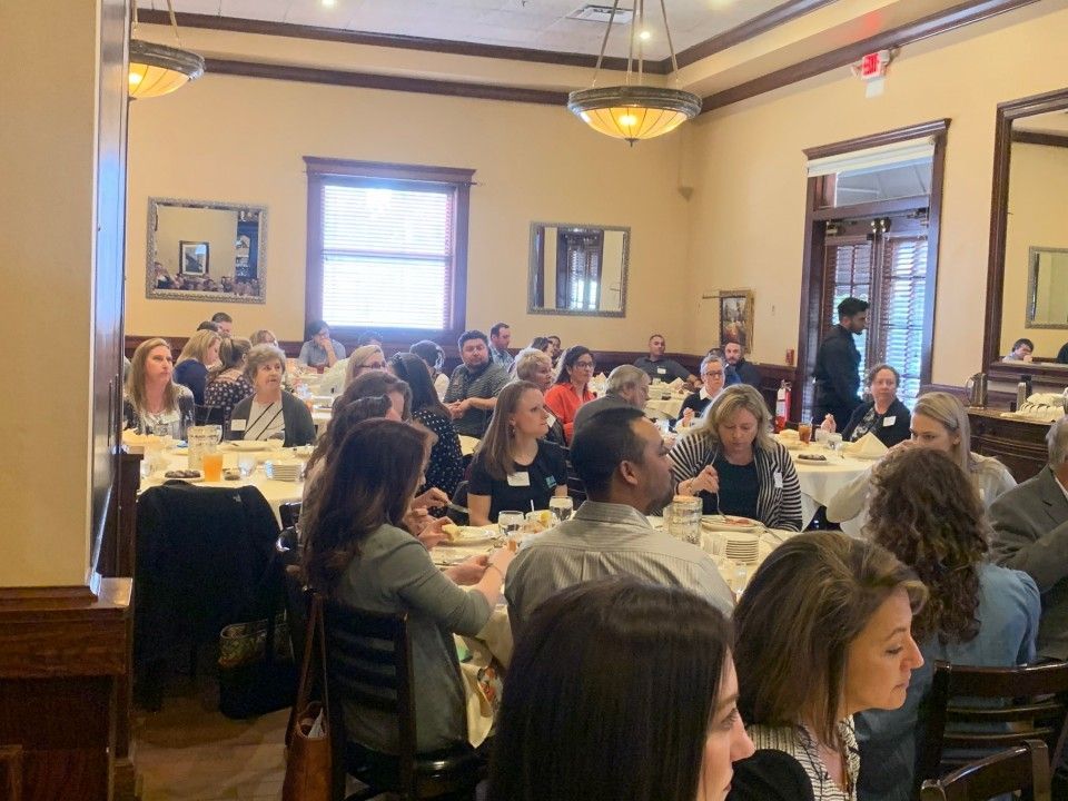 People seated at tables in a restaurant for a gathering or event.