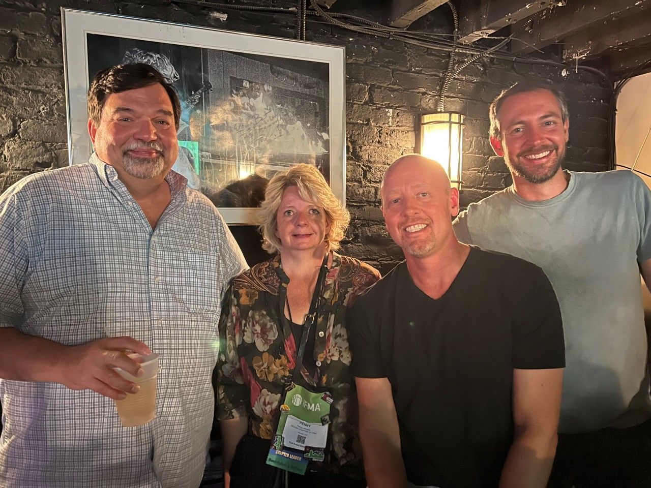 Four people pose closely together in a dimly lit room