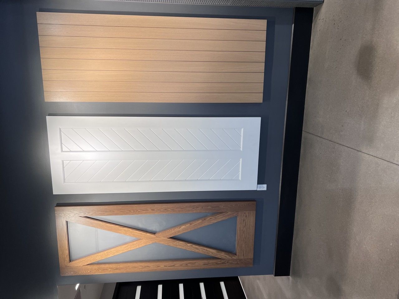 Three decorative wooden panels in different styles: light wood, white chevron, and brown X design.