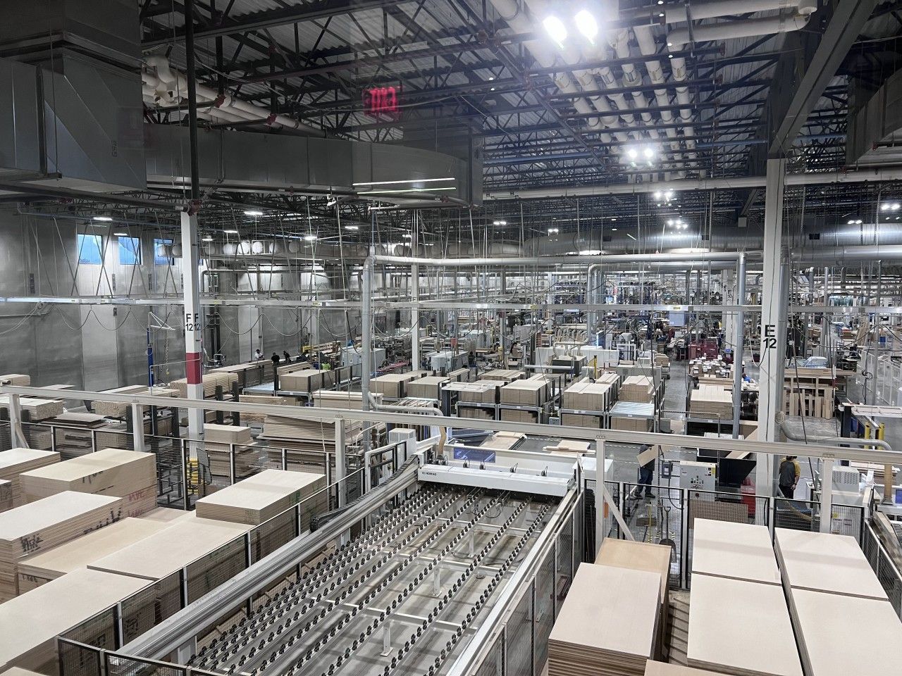 Warehouse interior with conveyor belts and boxes, overhead lighting.