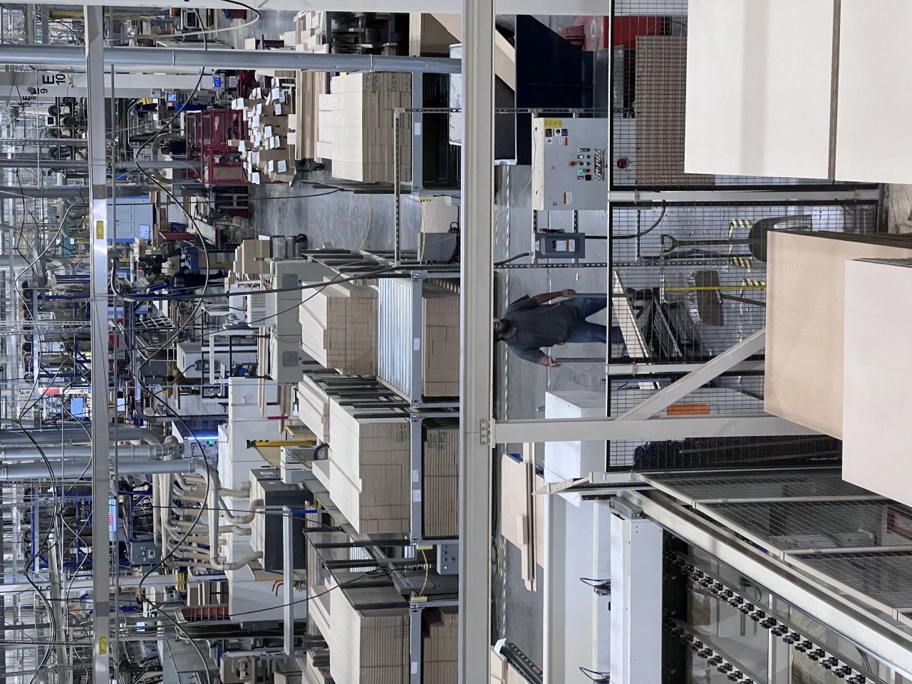 Warehouse interior with boxes on shelves and machinery. A person is near a conveyor belt.