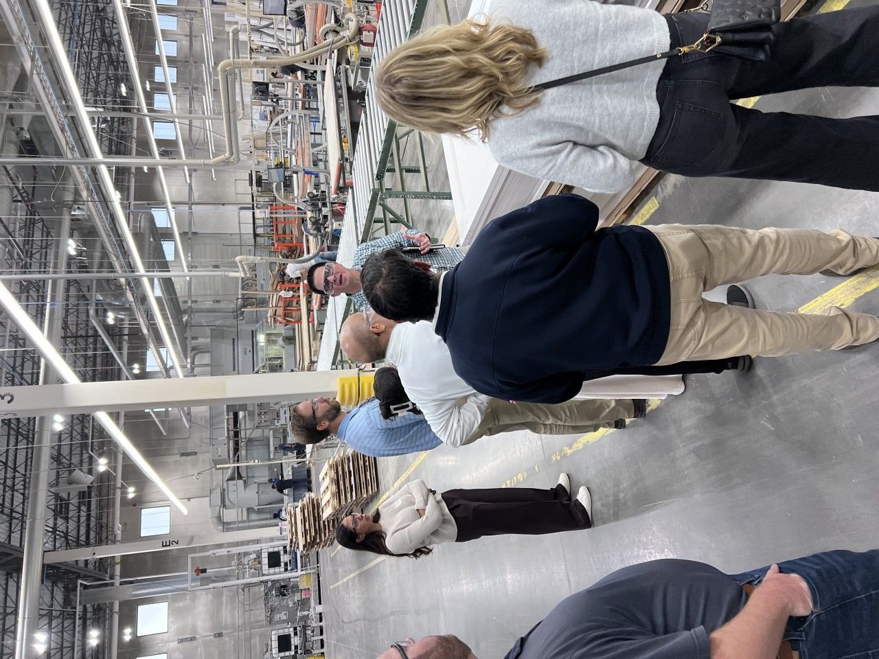 Group of people observing a manufacturing process in a factory. They are watching a demonstration.