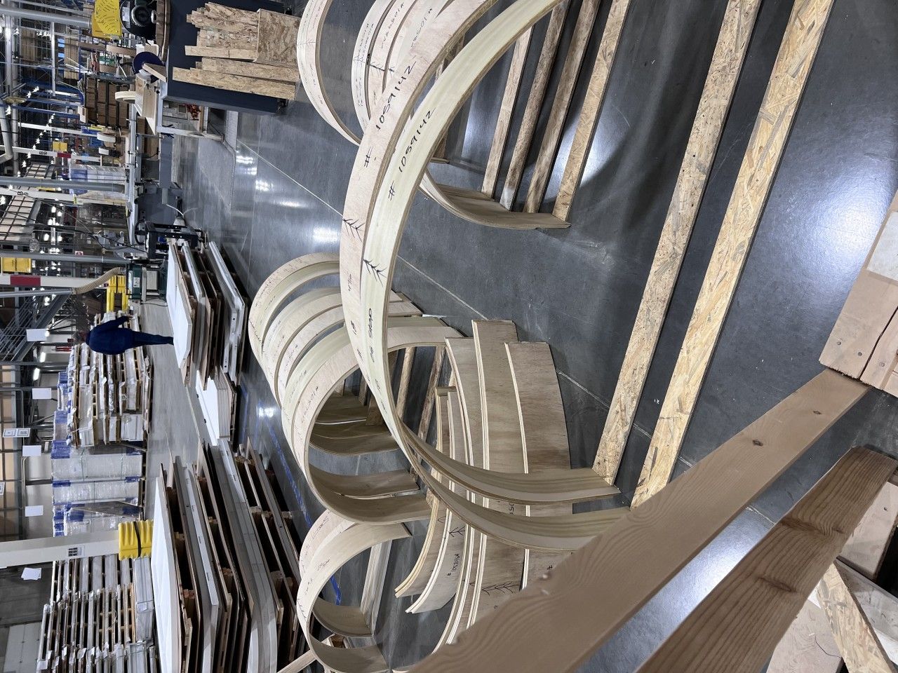 Wooden arches and planks in a warehouse setting. A person in blue walks nearby.