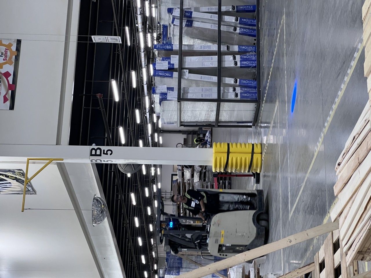 Forklift operating in a warehouse with shelves of inventory.