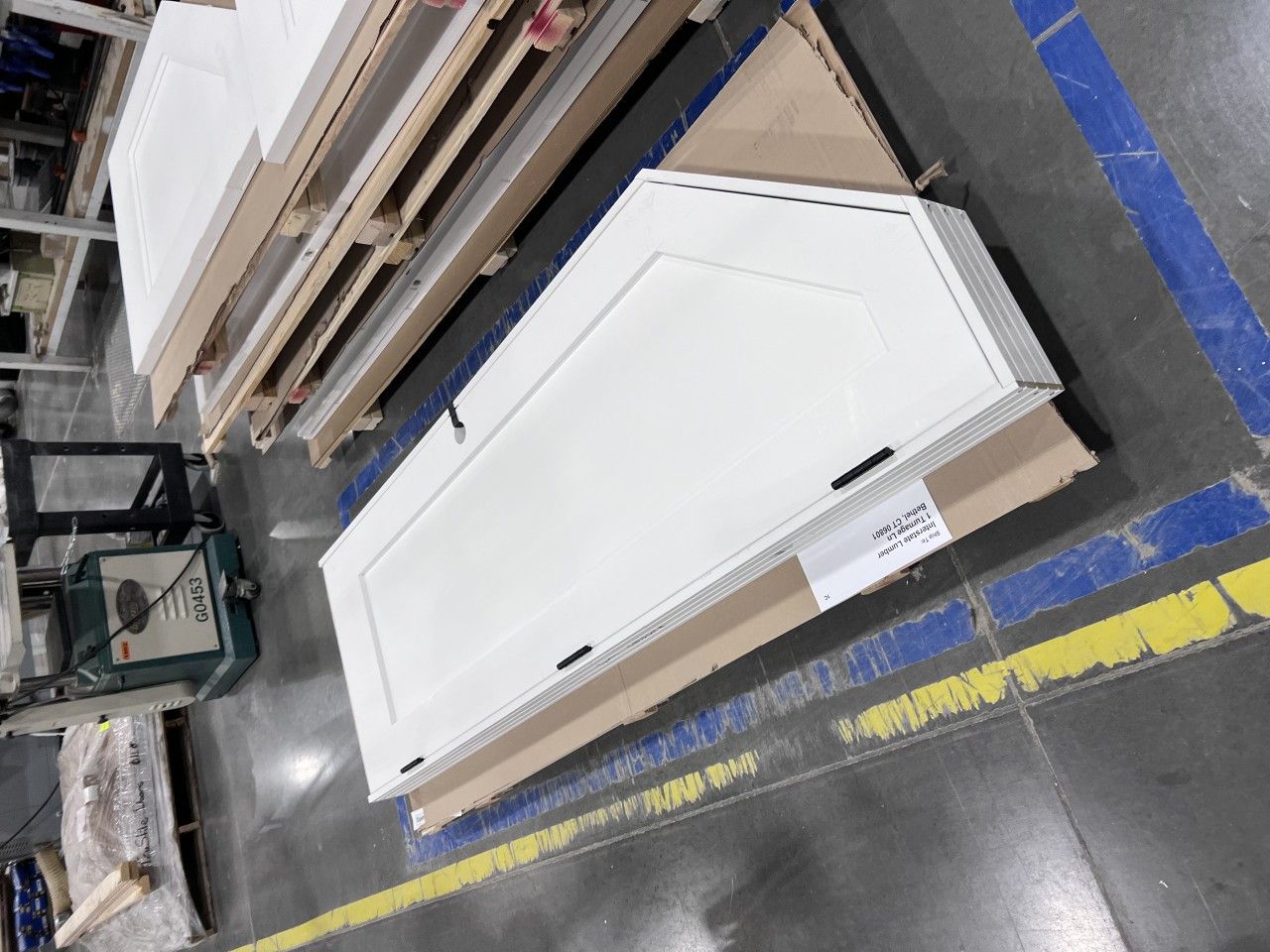 White door leaning against other doors, on a pallet, industrial setting.