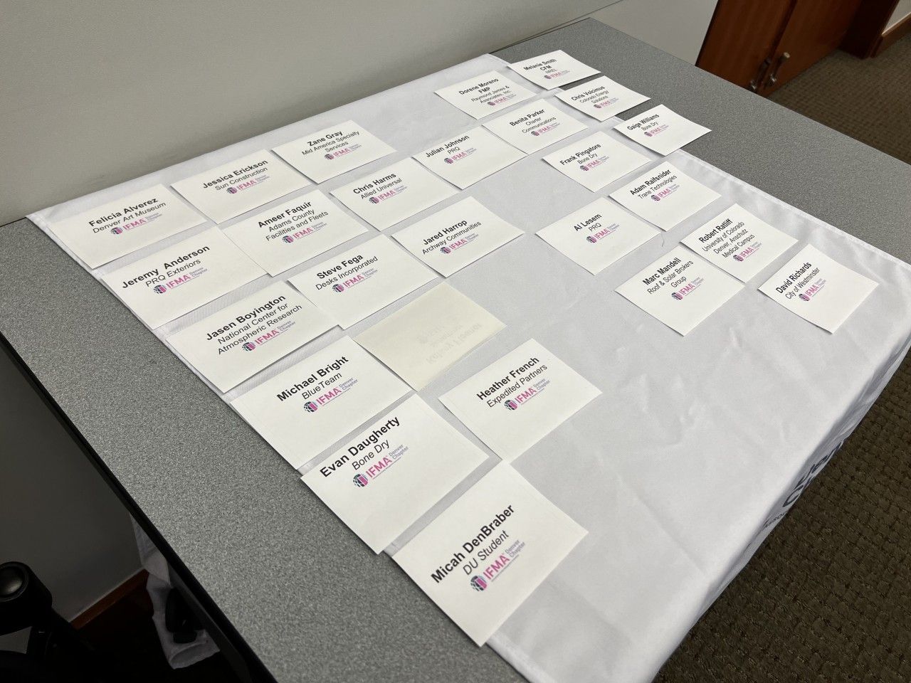 White napkins with names and a logo are arranged on a white tablecloth.