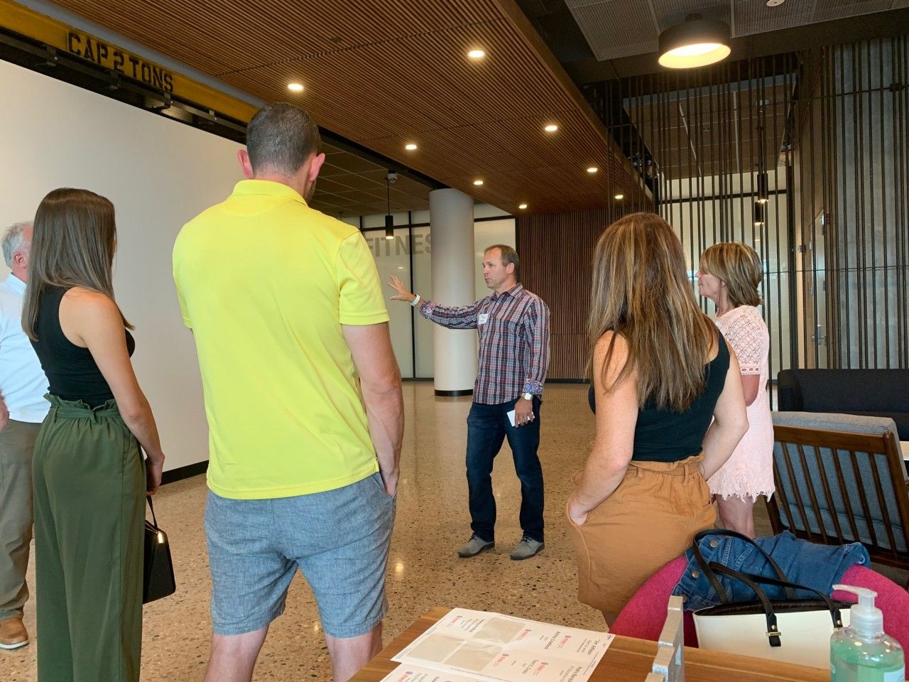Group of people on a tour in a modern building. A man gestures while speaking.