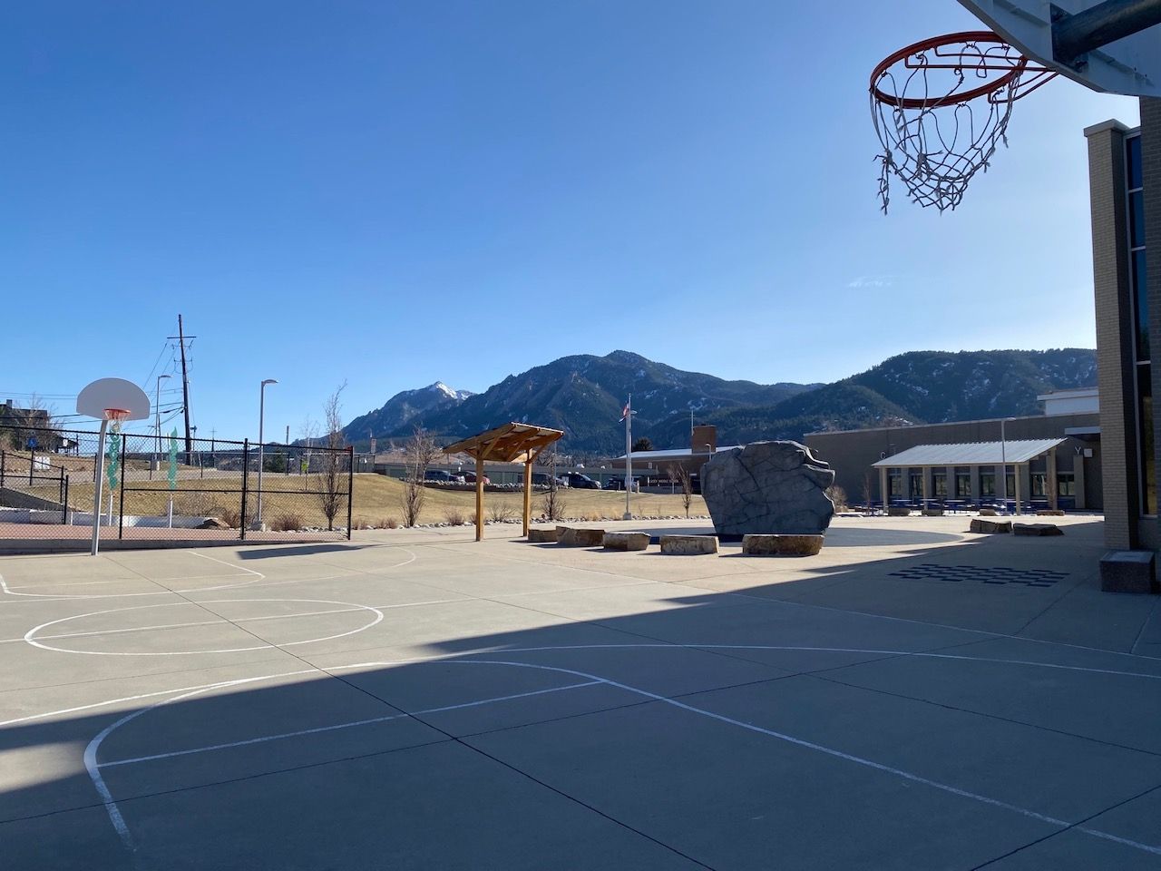 Basketball court with mountain backdrop and clear blue sky.