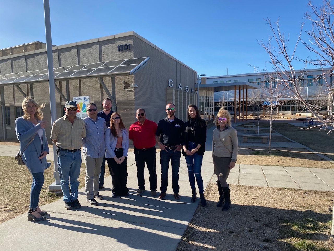 Group of people standing in front of a building on a sunny day.