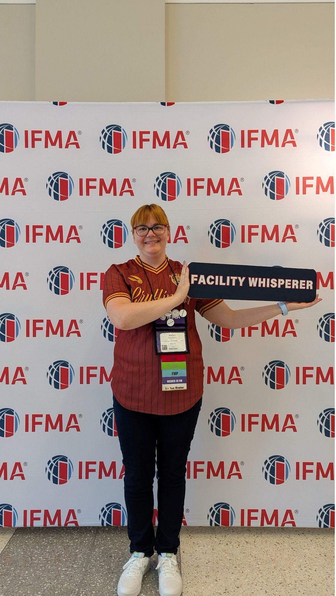 Woman with blonde hair smiling, wearing a blue denim shirt, indoors.