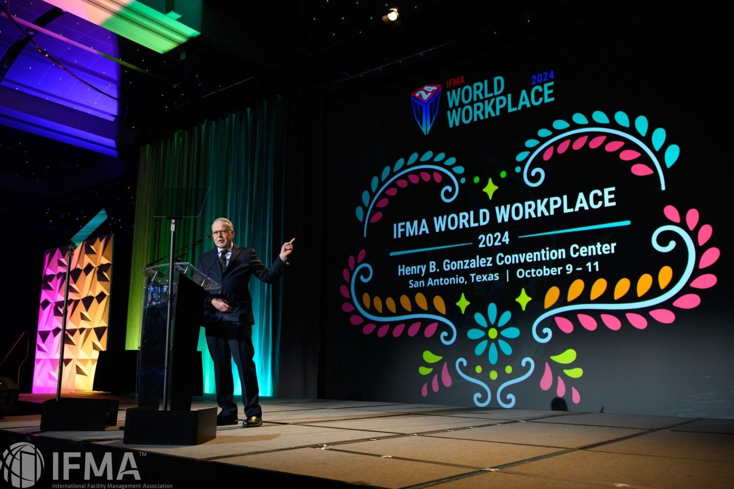 Man speaking at IFMA World Workplace 2024 conference on stage with event logo at Henry B. Gonzalez Convention Center.
