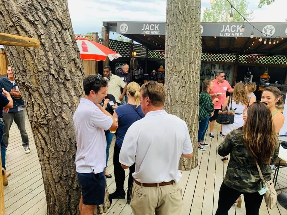 People gathered at an outdoor restaurant, some talking and drinking.  