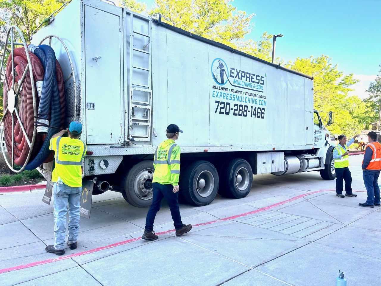 Truck from Express Sewer & Drain Cleaning with workers wearing safety vests on a paved surface.
