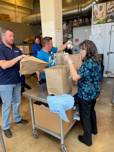 People packing brown paper bags at a food distribution center.