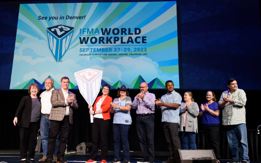 Group of people on stage, applauding under a 