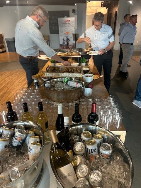 People at a buffet with food, drinks, and ice. Men serving themselves.