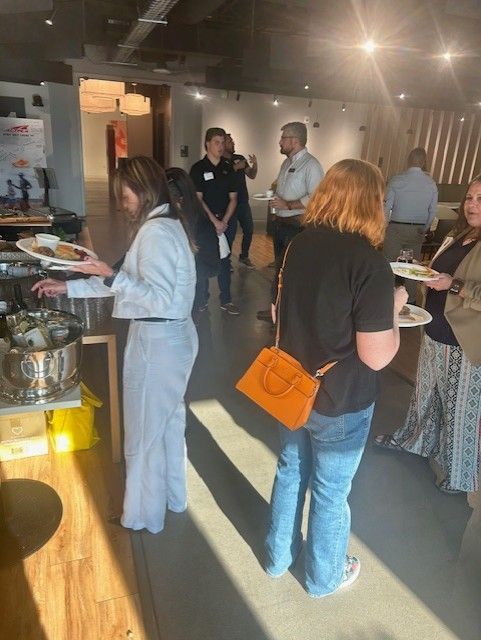 People at an event, serving food from buffet. Bright light, white and blue outfits.