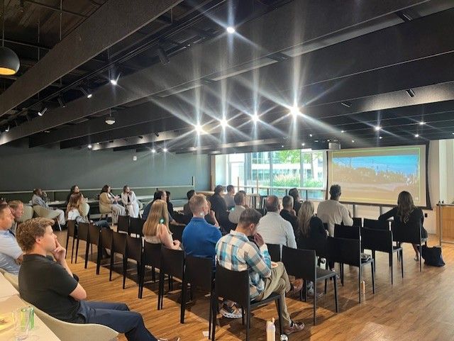 Audience watches a presentation on a screen in a modern conference room.
