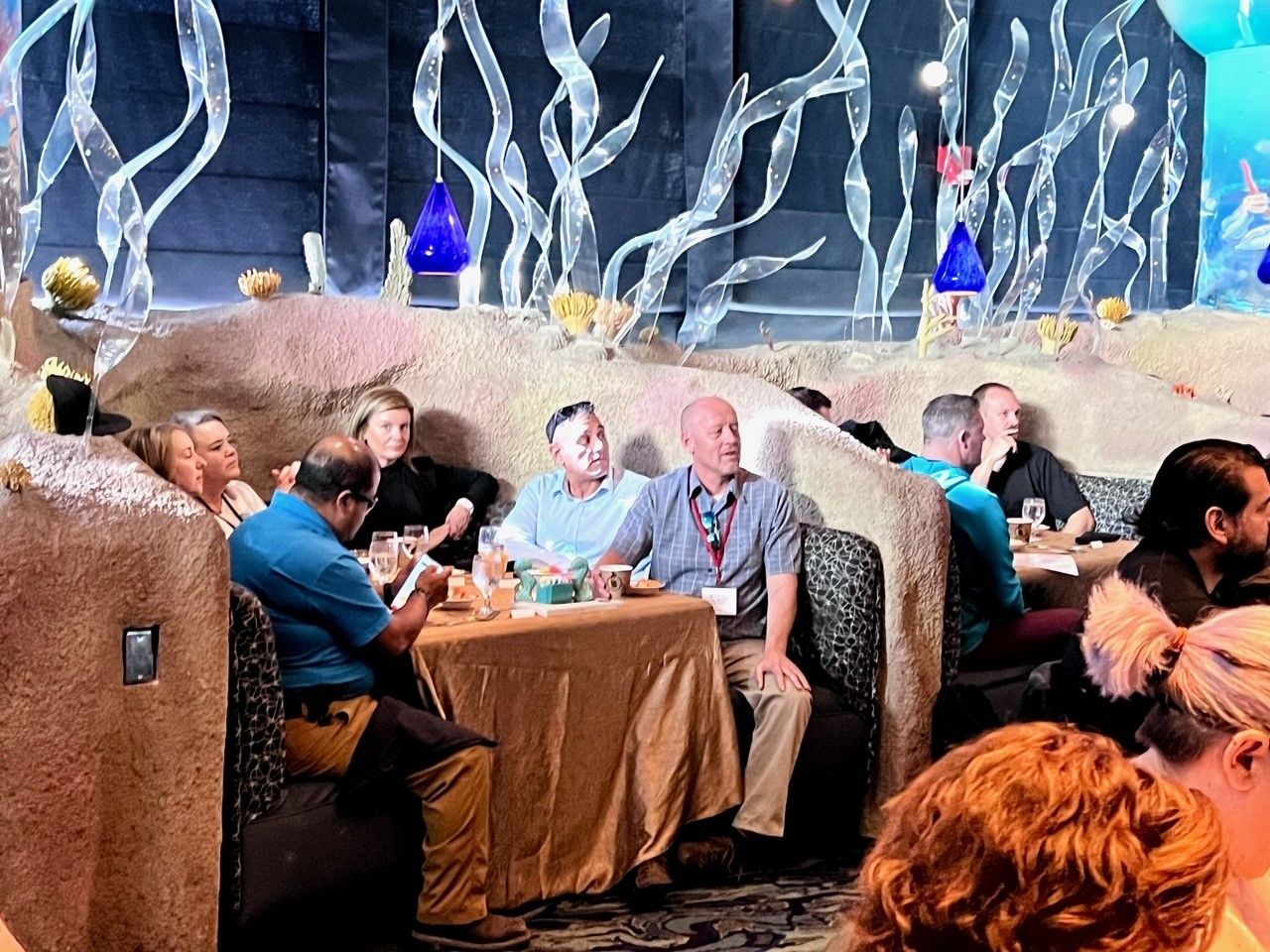 People seated at tables in a themed restaurant with sea-like decor.