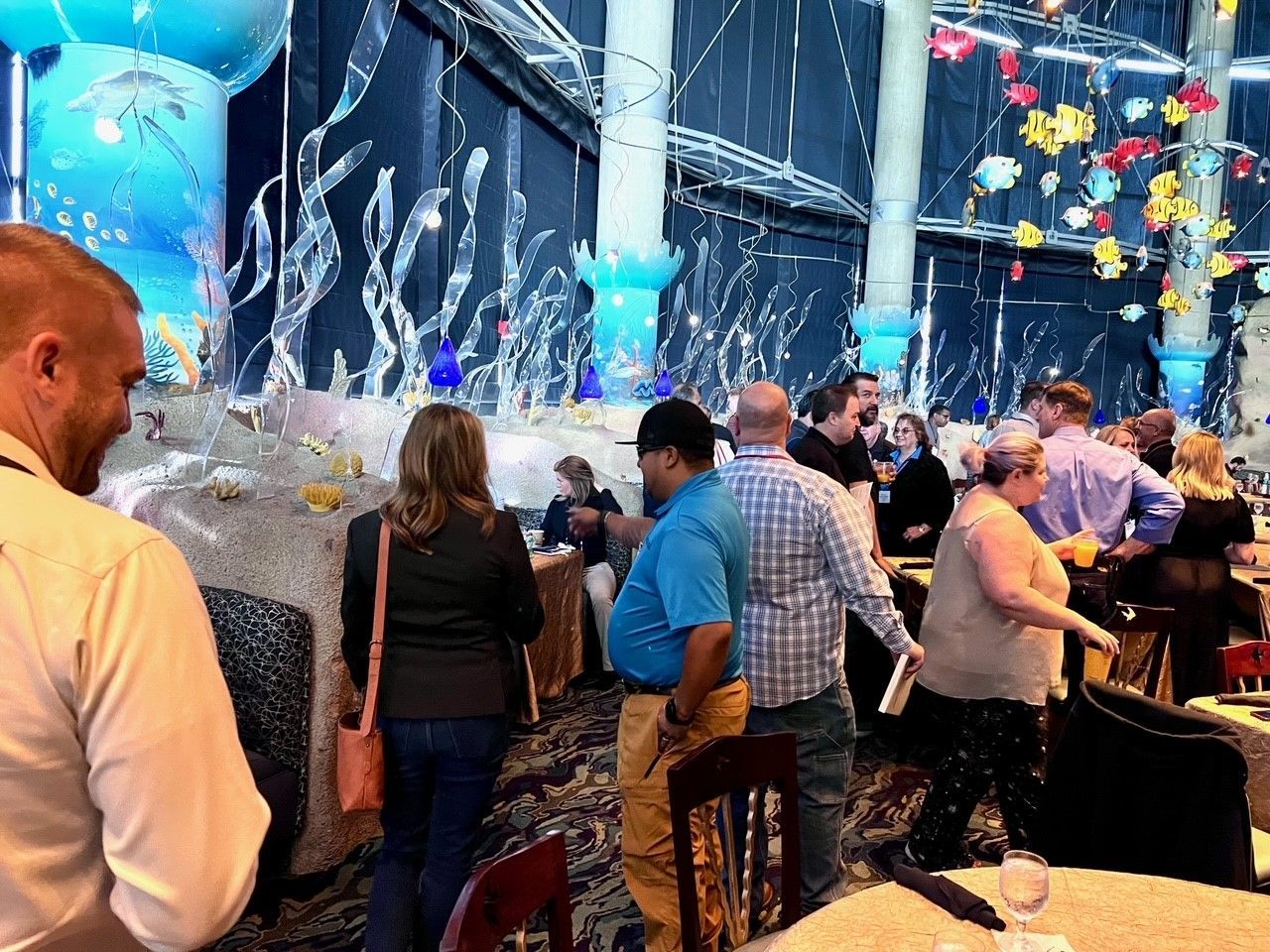 People gather in a decorated room with aquatic-themed decor.