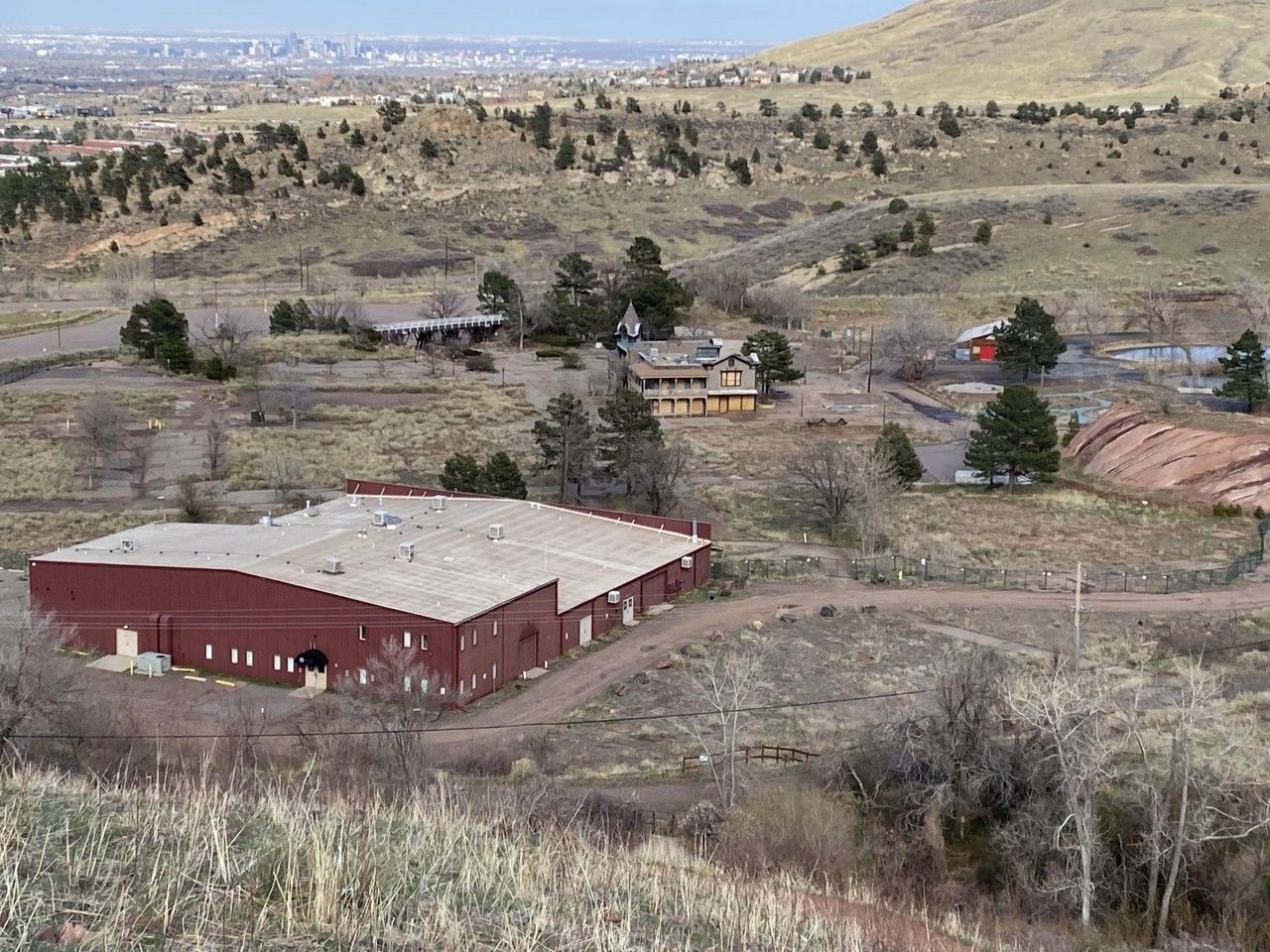 A complex of buildings in a dry, hilly landscape. A large red warehouse is in the foreground.