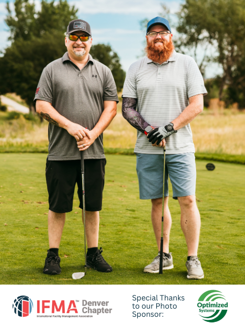 Two men on a golf course holding clubs; one has a beard, arm sleeve; they smile.