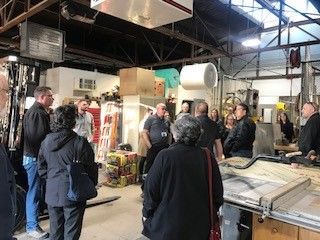 Group of people in a workshop, looking at equipment and listening to a discussion.