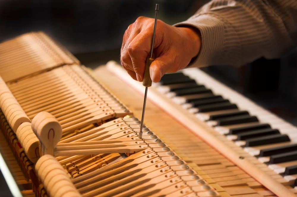 A Person Is Working on A Piano with A Screwdriver — David Simpson Pty Ltd in Port Douglas, QLD