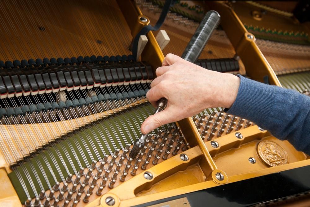 A Person Is Working on A Piano with A Screwdriver — David Simpson Pty Ltd in Redlynch, QLD