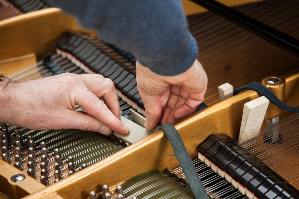 A Person Is Working on The Inside of A Piano — David Simpson Pty Ltd in Port Douglas, QLD