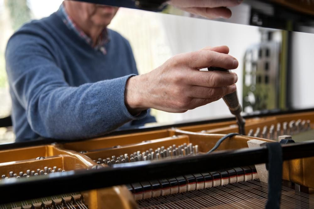 A Man Is Working on A Piano with A Screwdriver — David Simpson Pty Ltd in Innisfail, QLD