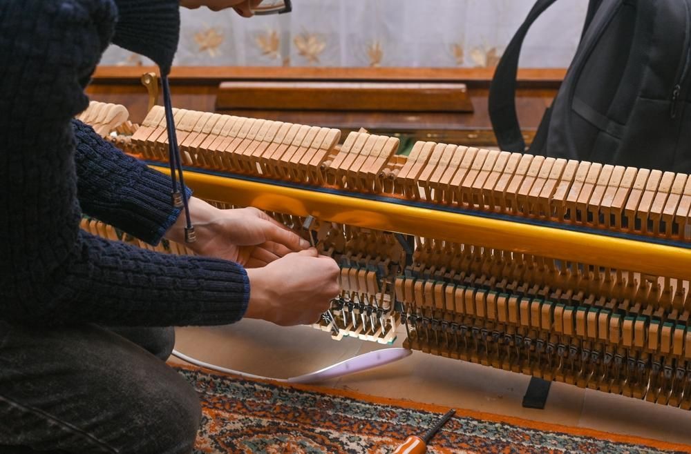 A Man Is Working on A Piano with A Pair of Scissors — David Simpson Pty Ltd in Redlynch, QLD