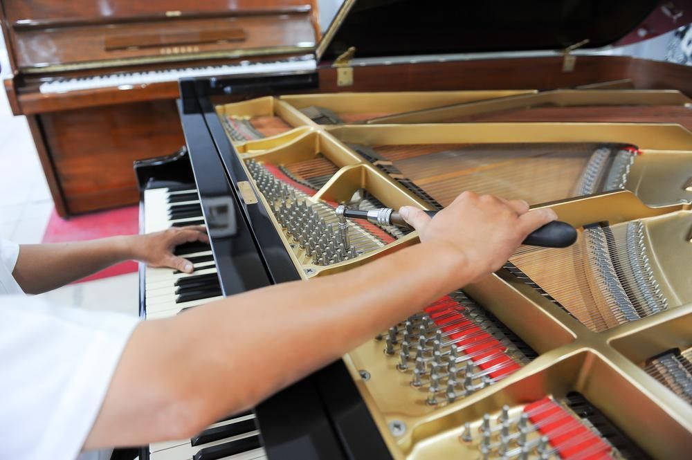 A Person Is Working on A Piano with A Screwdriver — David Simpson Pty Ltd in Port Douglas, QLD