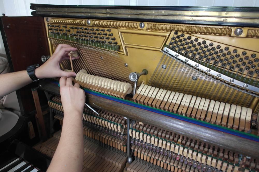 A Person Is Working on A Piano with A Screwdriver — David Simpson Pty Ltd in Port Douglas, QLD
