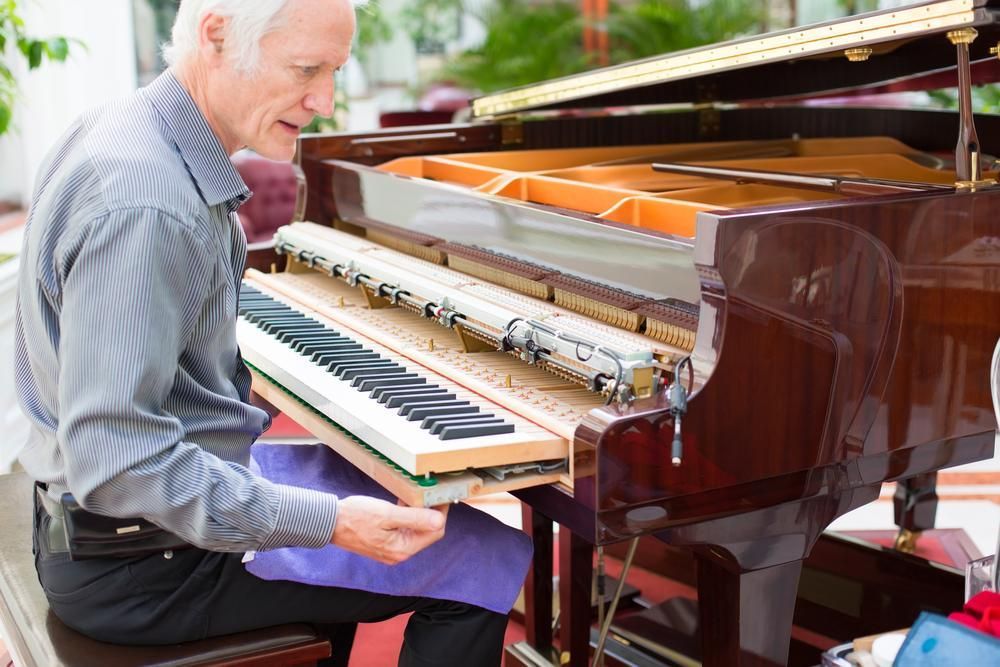 A Man Is Sitting at A Piano Looking at The Keys — David Simpson Pty Ltd in Port Douglas, QLD