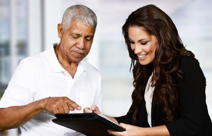 Older man and younger woman looking at tablet; man points to screen, woman smiles.
