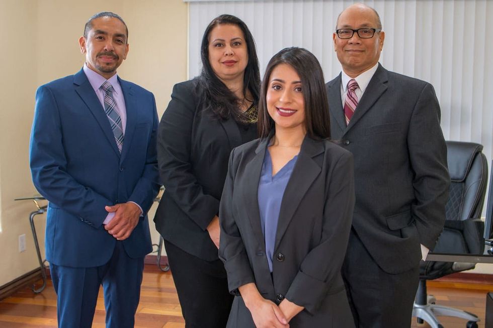 Four professionals in suits posing in an office setting.