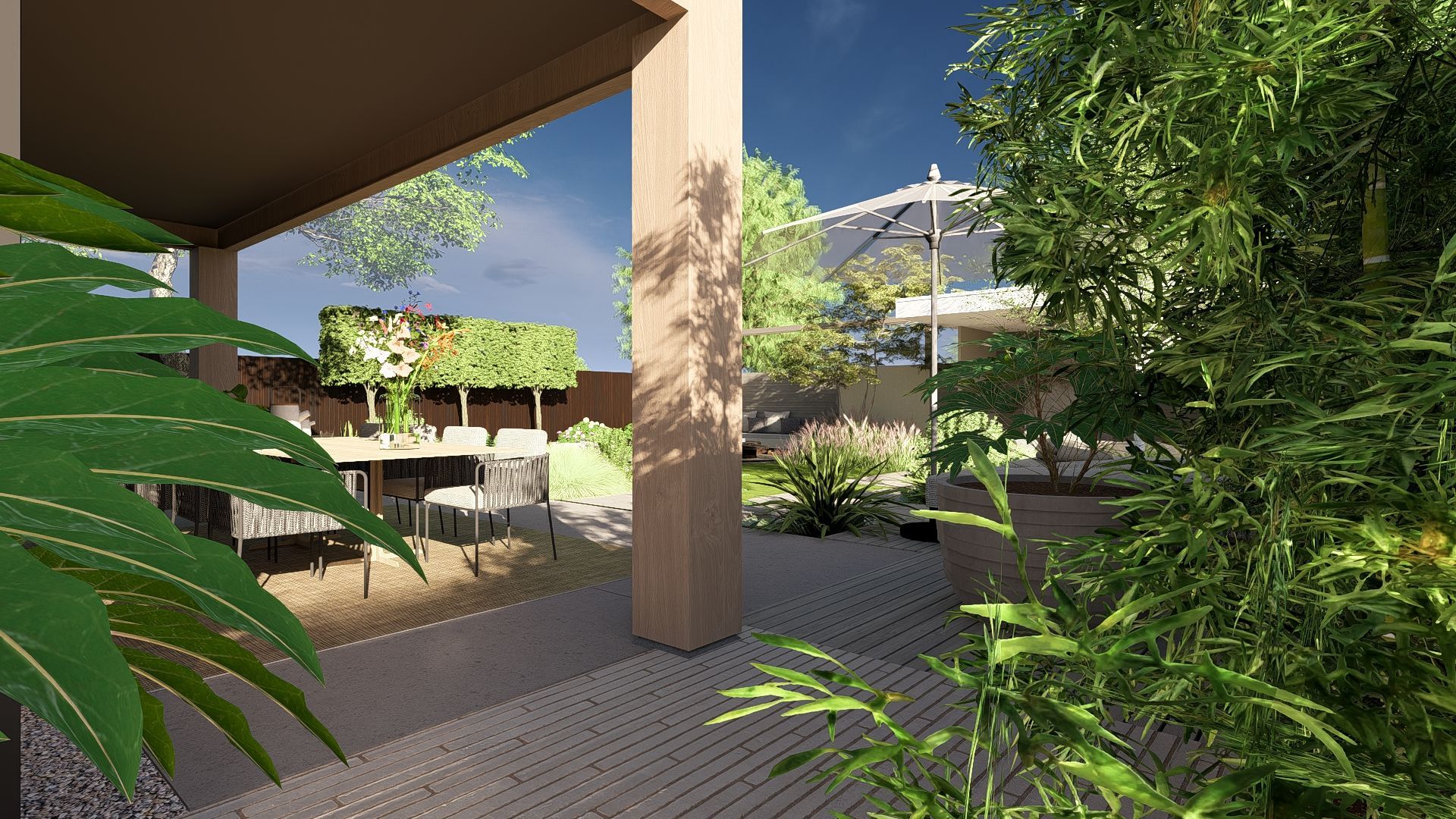 Terras met stenen bestrating, beige pilaren en weelderig groen. Zonlicht schijnt door de bomen naar een gebouw in de verte.