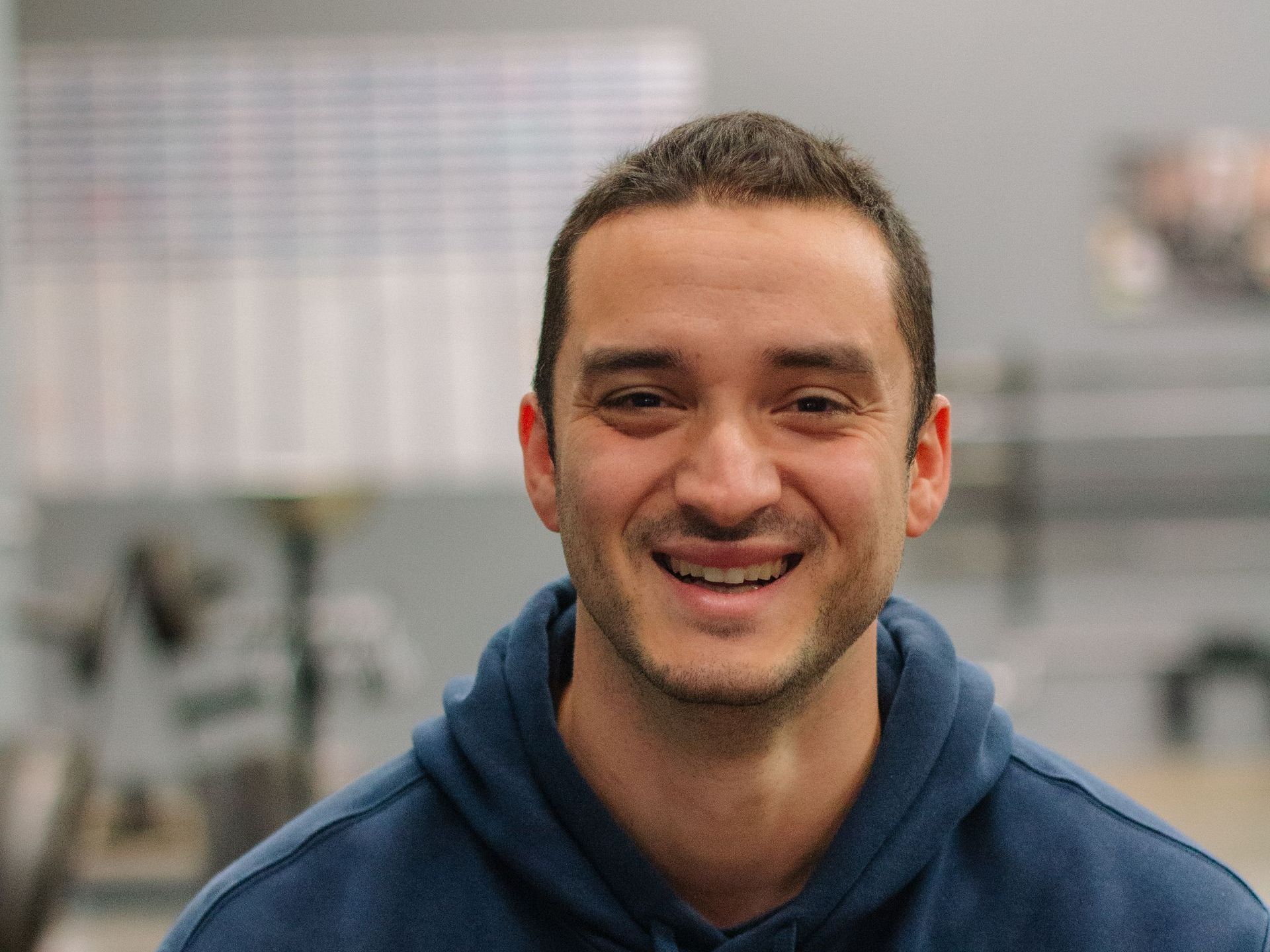 A man in a blue hoodie is smiling for the camera.