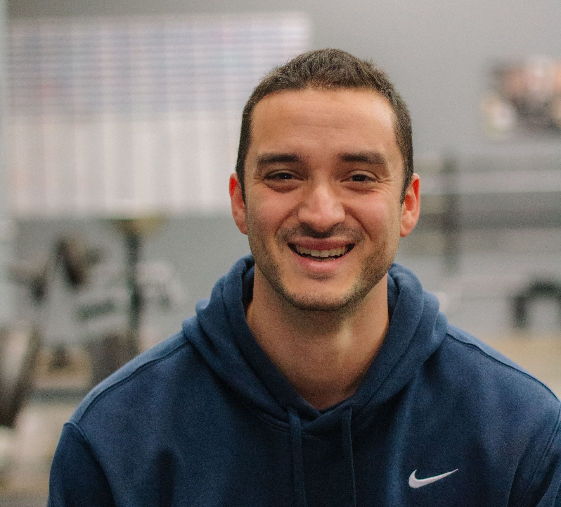 A man in a blue hoodie is smiling for the camera.