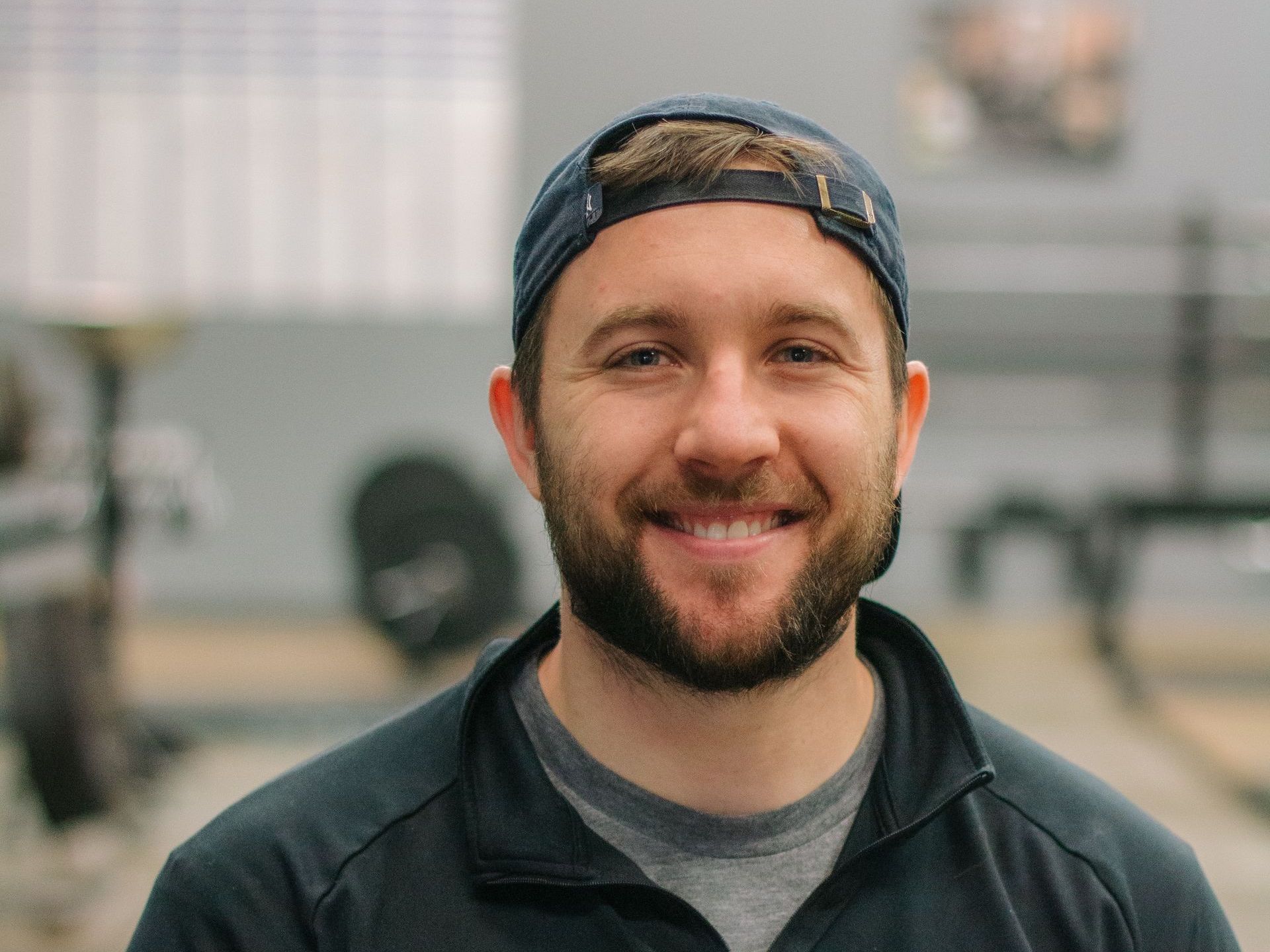 A man with a beard and a hat is smiling for the camera.