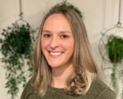 A man with a beard wearing a bandana is sitting at a desk.