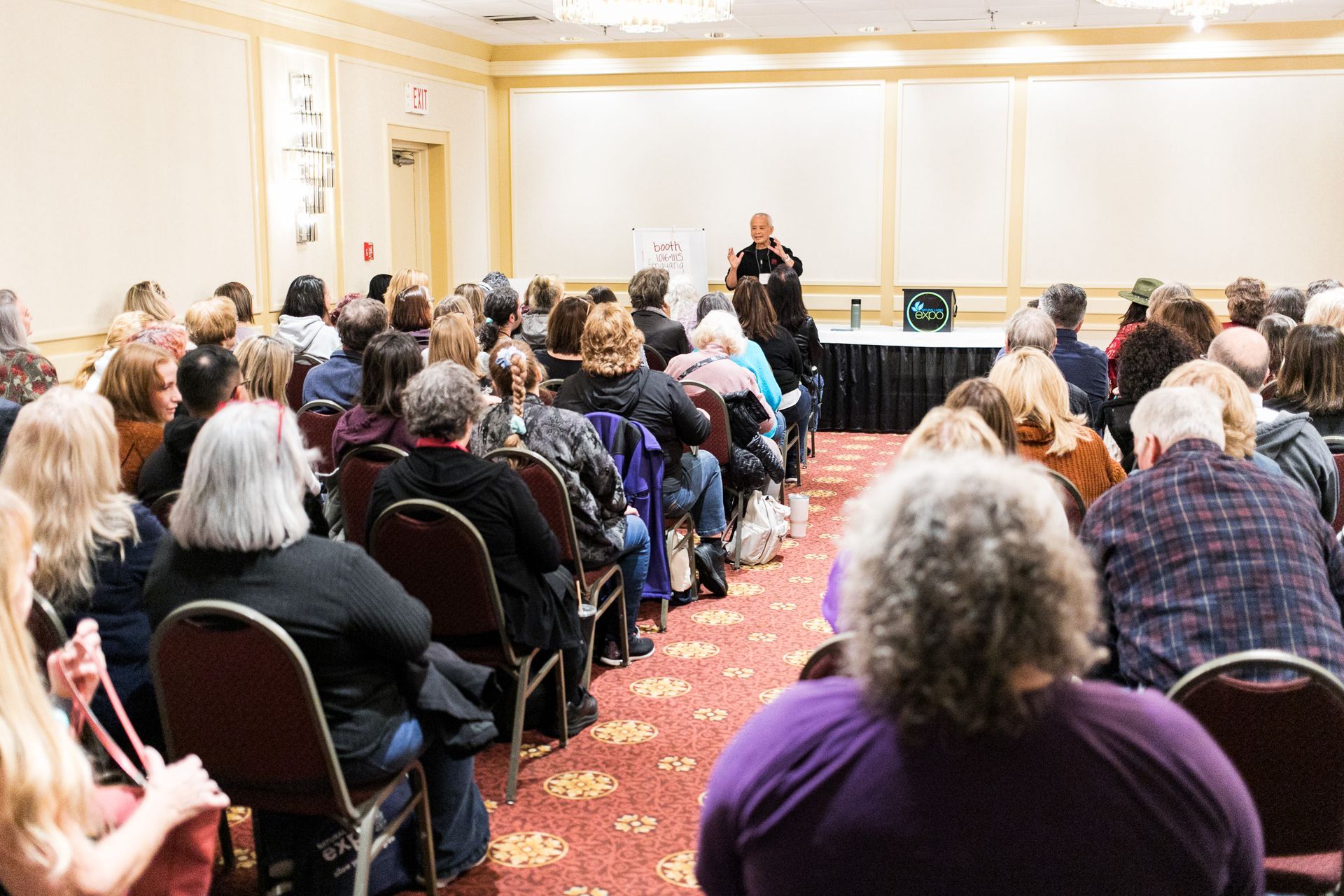 A large group of people are sitting in a room watching a presentation