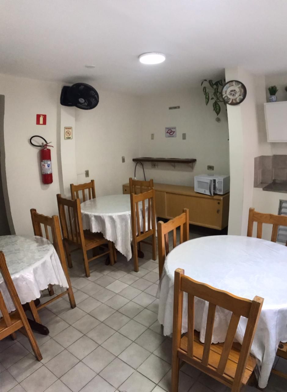 Uma sala de jantar com mesas redondas cobertas com toalhas de mesa brancas e cadeiras de madeira.