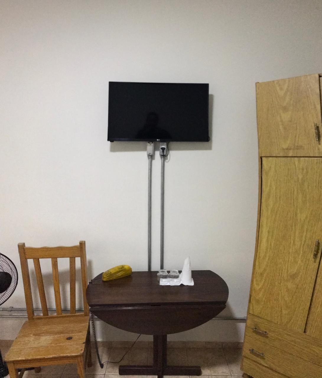 Televisão, cadeira com armário próximos.