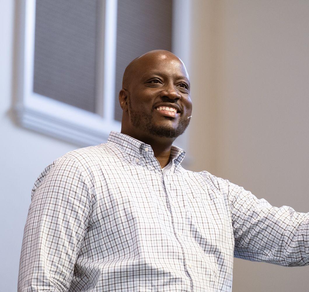 William Givens in a plaid shirt is standing and smiling.