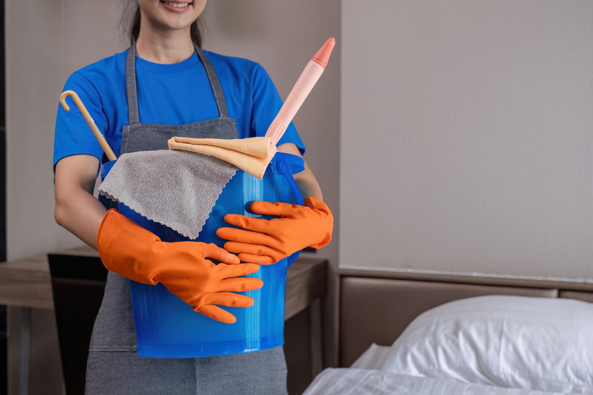A woman is holding a bucket of cleaning supplies