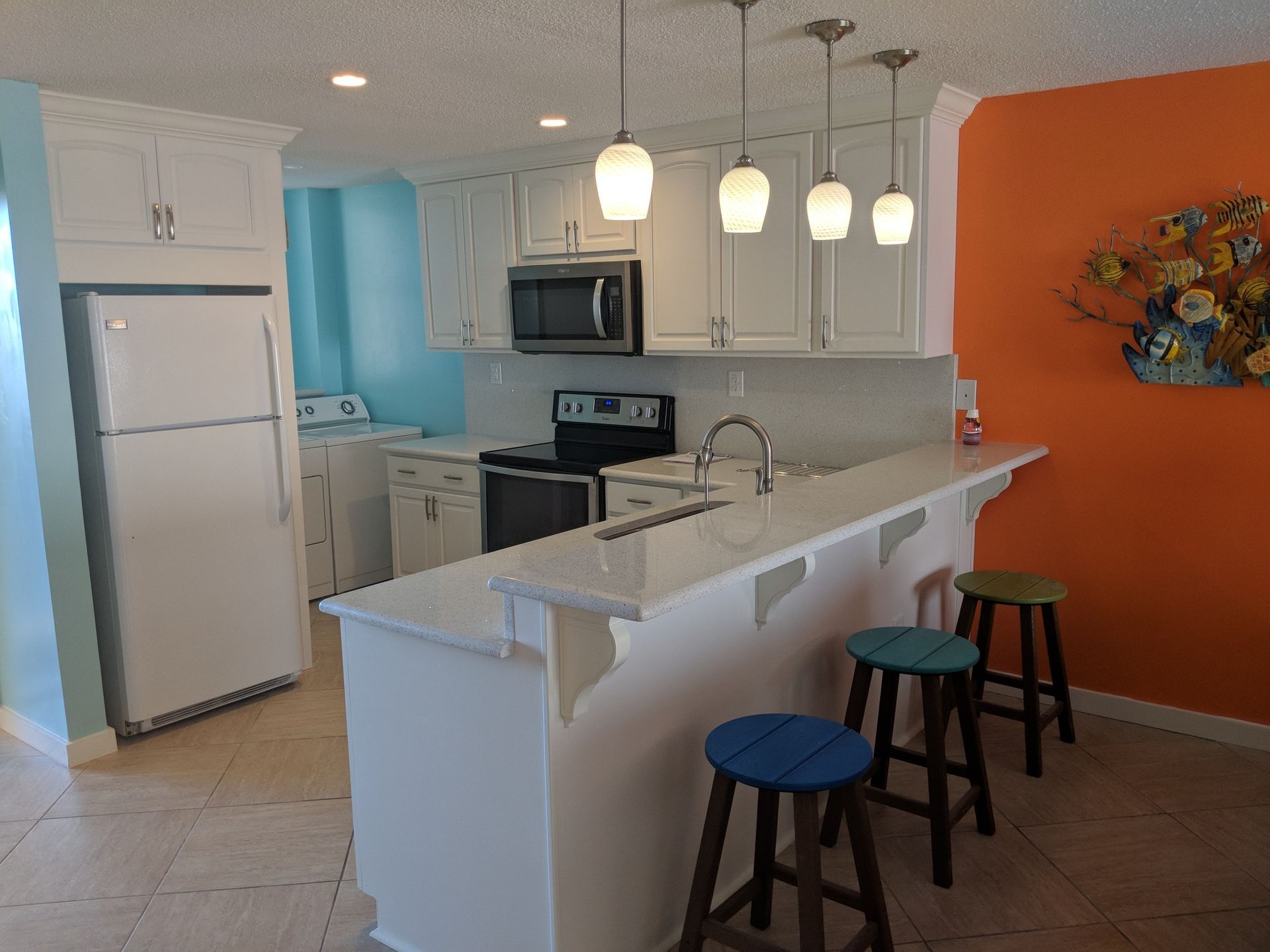 Kitchen with white cabinets, stainless steel appliances, breakfast bar with stools.